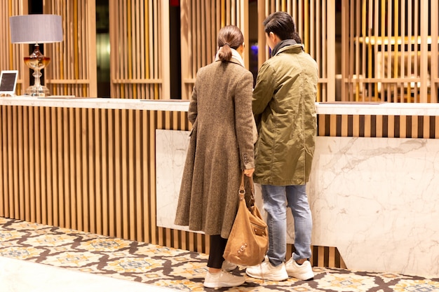 Asian couple checking in the hotel at hotel reception.