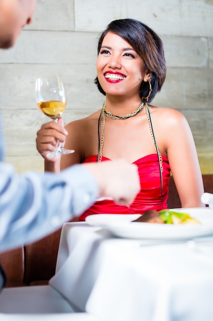 Asian couple clinking wine glasses in bar