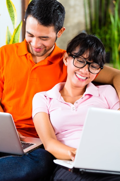 Asian couple on the couch with a laptop