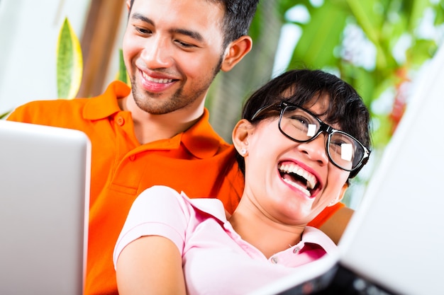 Asian couple on the couch with a laptop