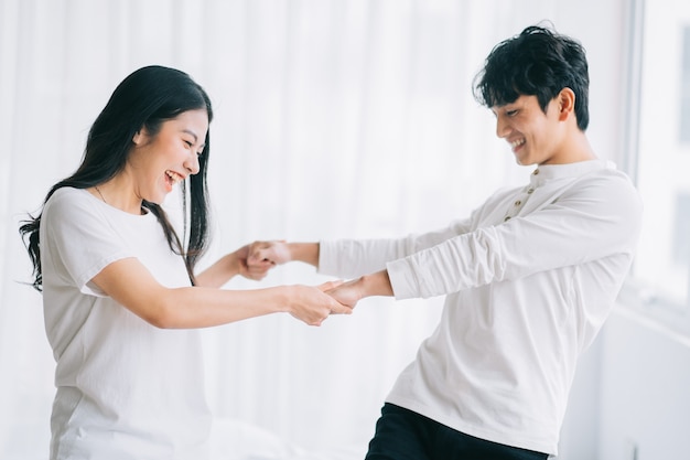 Asian couple dancing together in the bedroom