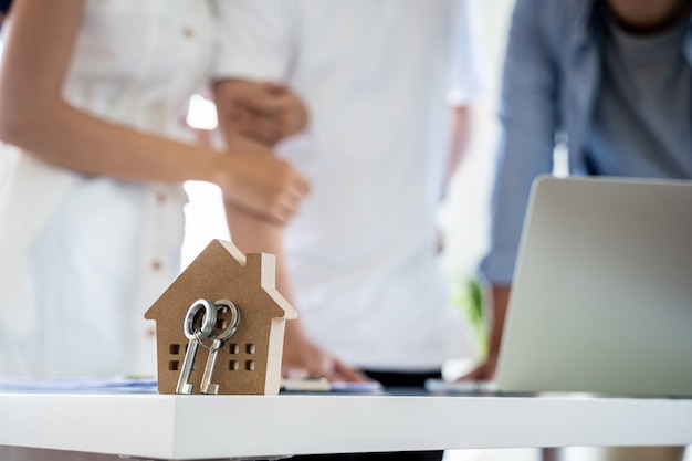 Asian couple Decide to buy a new house from laptop with Real estate agent, subject is a house model with key