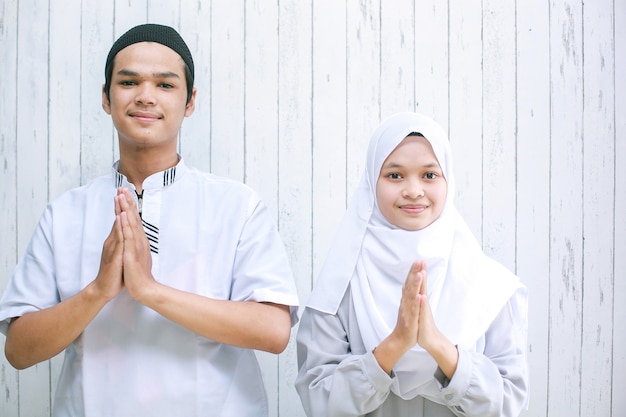 Asian couple doing muslim handshake into the camera for Eid Al Fitr celebration greeting