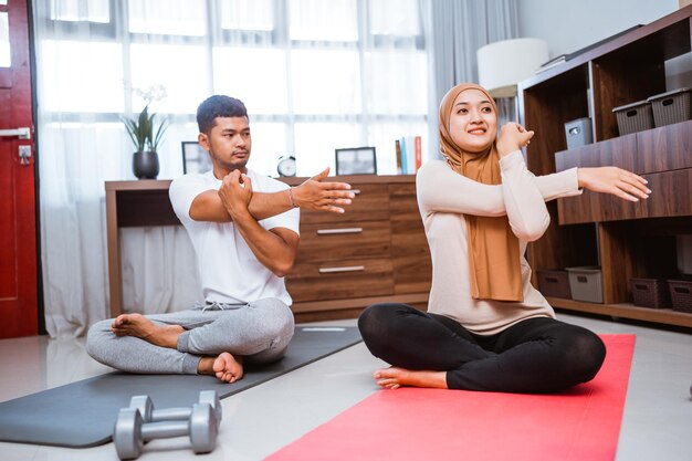 Asian couple doing partner workout and stretching together at living room