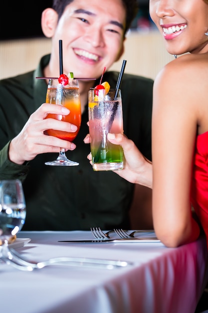 Asian couple drinking cocktails in fancy bar