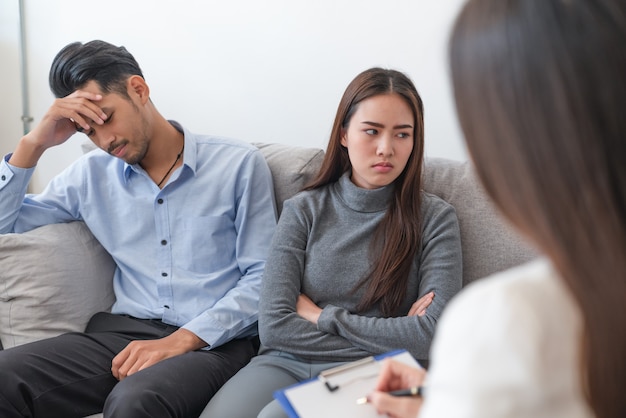 Asian couple have problems sitting on so sofa their getting advice and consult from woman psychiatrists