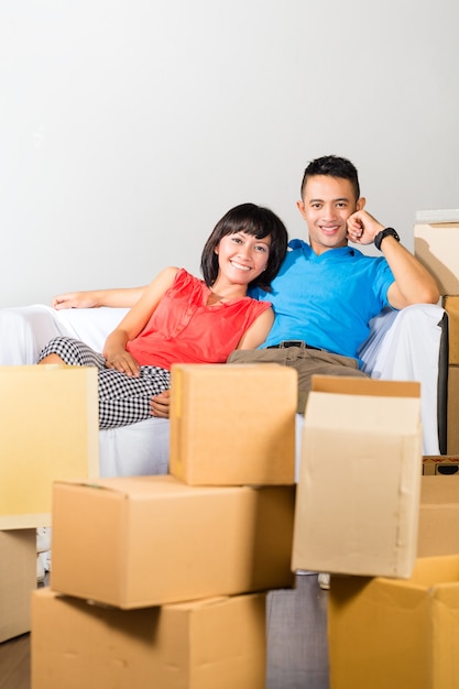 Asian couple having break while moving in