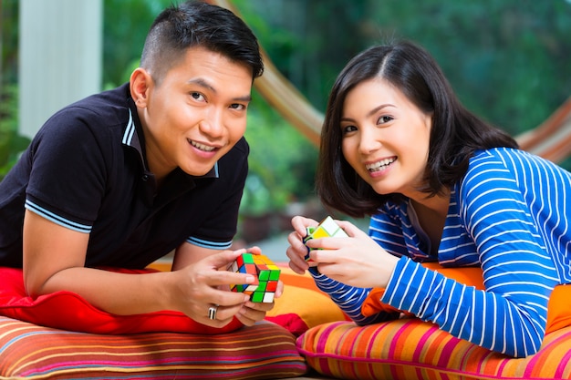 Coppie asiatiche a casa che giocano con il cubo magico