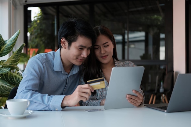 디지털 태블릿과 신용 카드로 온라인 쇼핑을 하는 아시아 커플