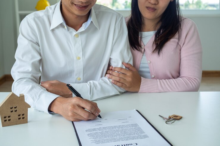 फोटो asian couple is signing a mortgage contract or buying house. the husband and wife agreed to buy or sell the house after talking to a salesperson. the concept of a contract and sign.