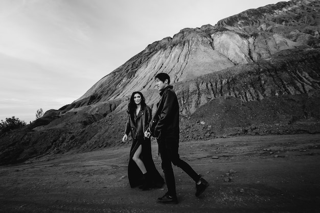 An Asian couple in love in black leather clothes walk in nature among the trees. Black-white