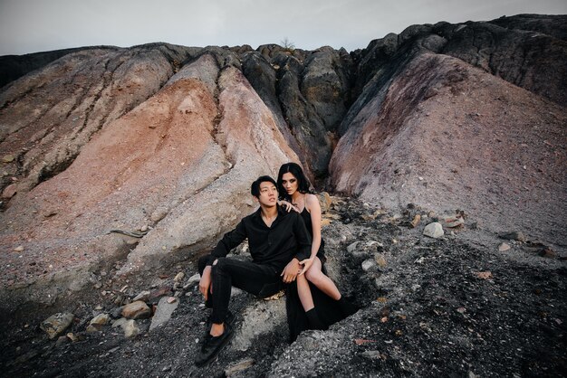 Asian couple in love hugs sitting on the rocks. Love story