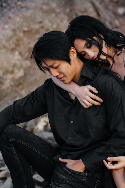 asian couple in love hugs sitting on the rocks. love story