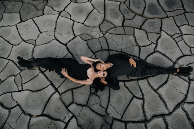 An Asian couple in love hugs while lying on the ground.