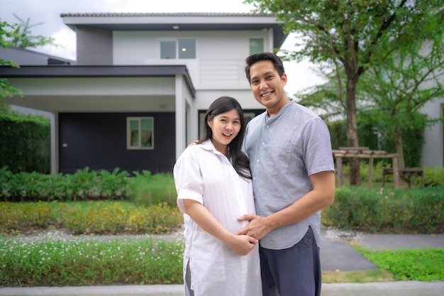 Asian couple outside new house for starting new family husband touching his wife pregnant belly