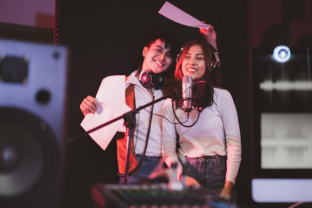 Asian couple singers in a recording studio using a studio\
microphone with passion in music recording studio