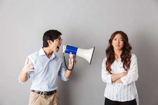 Asian couple standing, man yelling in a loudspeaker