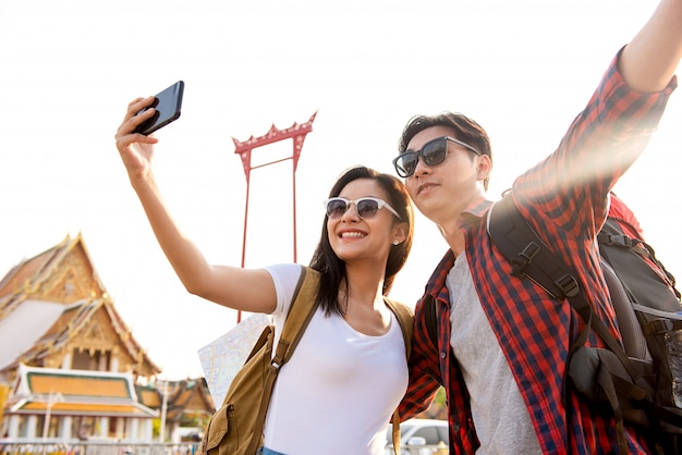 Asian couple tourists taking selfie while traveling in Bangkok Thailand