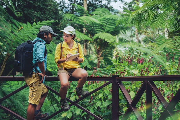 Asian couple travel nature walking relax and studying nature in the fores.