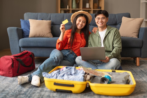 Asian couple using laptop and credit card booking tickets indoor