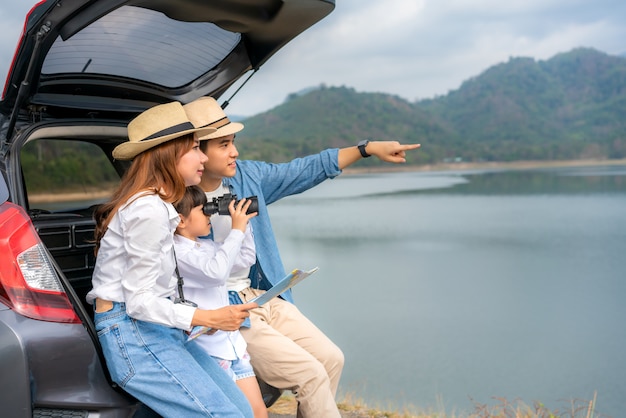 Asian couple with a map sitting in the back of the car