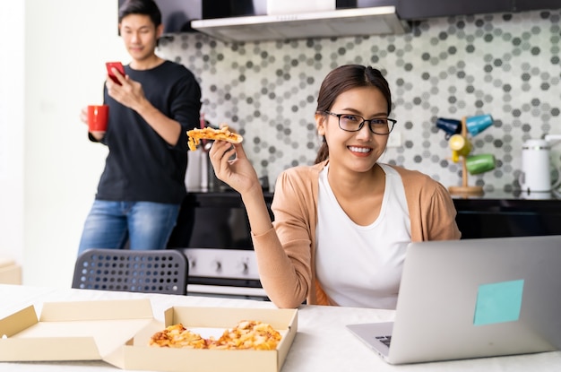 Asian couple work from home in the kitchen with delivery take away food