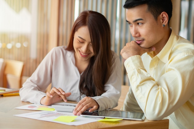 Le coppie asiatiche calcolano le entrate e le spese per tagliare le spese non necessarie e stanno pianificando di prendere in prestito denaro per acquistare una nuova casa. concetti per la pianificazione degli investimenti e la pianificazione finanziaria per la famiglia