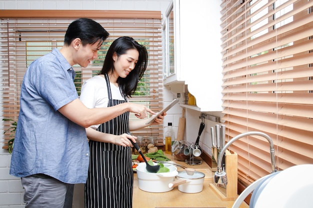 Asian couples cook together in their home kitchens
