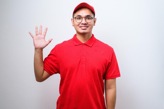 自信を持って笑っている間、配達のユニフォームとキャップを身に着けているアジアの宅配便の男は、指番号10を示して上向きにしています
