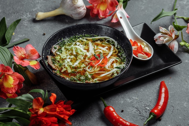 Asian cuisine, Beef soup fo in a black plate on a dark.