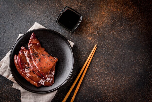 アジア料理、珍味。生牛レバーの照り焼きソースと黒ゴマ、暗いさびたテーブルトップビュー