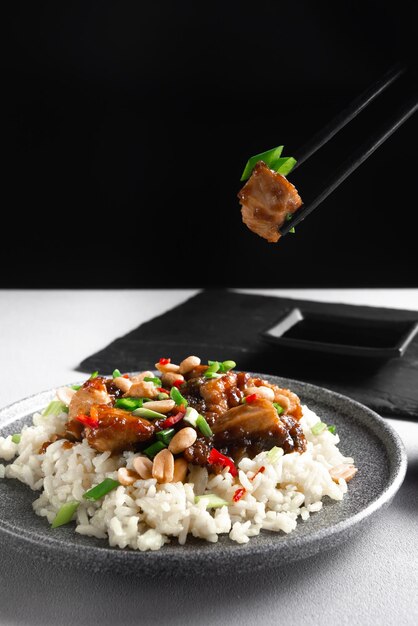 Asian cuisine a womans hand holds asian food sticks rice with chicken on a gray background view from