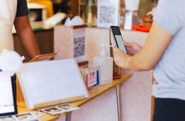 Asian customer women paying by QR code scanning on mobile phone at coffee shop