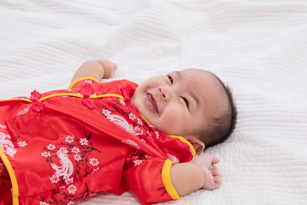 아시아 귀여운 아기 중국 치파오 의상 유아 집에서 침대에 누워 웃는 좋은 유머 웃고, 유아 중국 호기심 소년 아이, 뭔가 찾고, 해피 중국 설날 개념