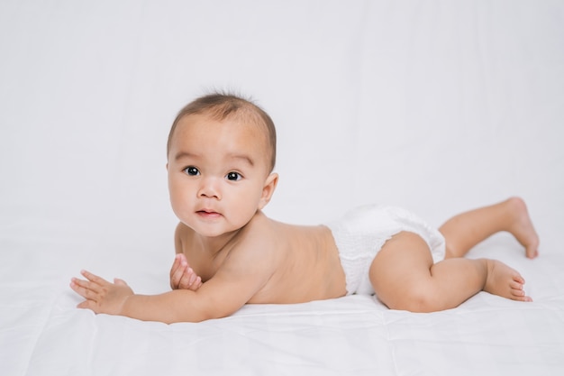 Asian cute baby boy on white bed in room