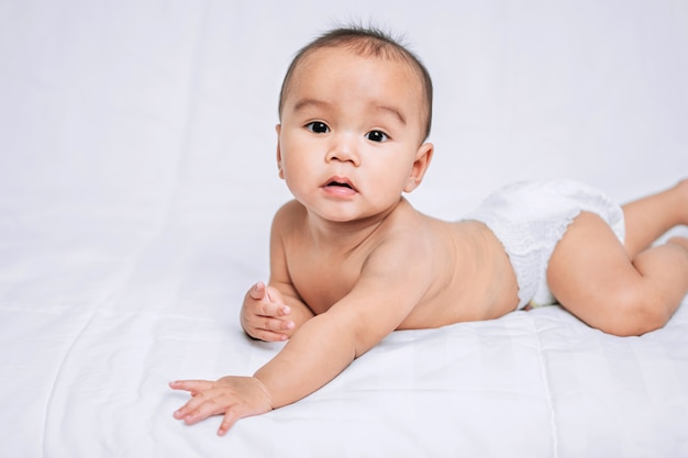 Asian cute baby boy on white bed in room