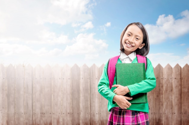 Asian cute girl with a backpack holding the book standing