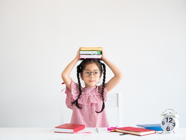 Ragazza carina asiatica con il libro sulla scrivania