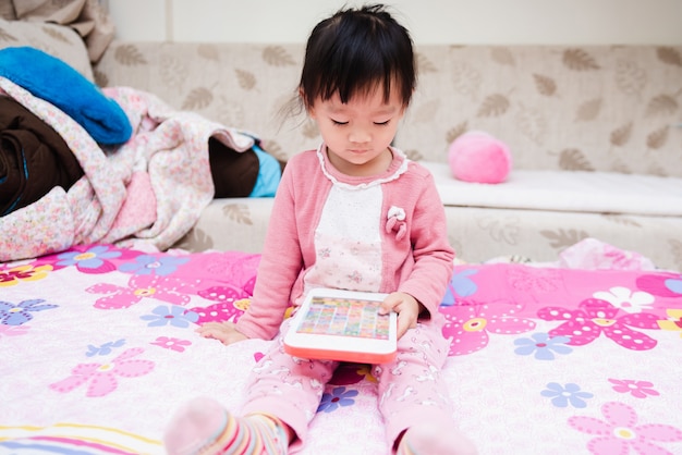  Asian cute little child playing game over the bed in a relaxed morning