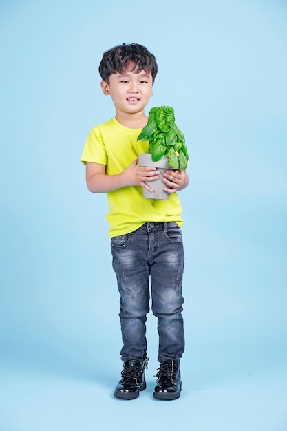 Asian cute little handsome boy hold a pot of green plant and smile, eco friendly concept