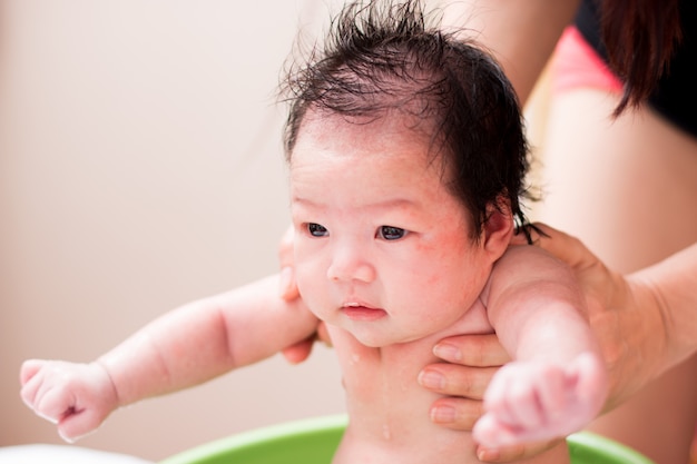 Asian cute new born having a bath by mother.