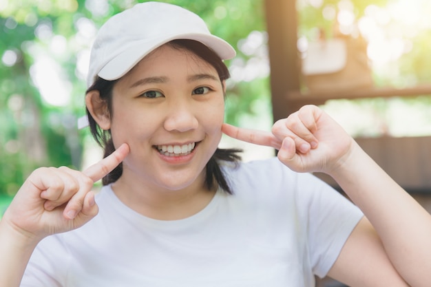 Asian cute teen good dental health smiling finger at her cheeks