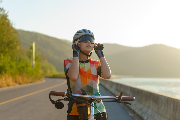 サングラスをかけて朝の自転車に乗る準備をしているアジアのサイクリストの女性