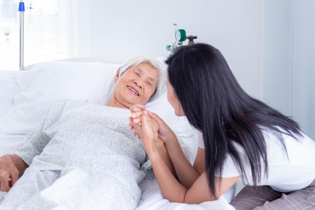 Asian daughter encourages and comforts elderly female patient at hospital