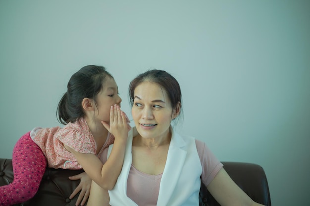 Asian daughter girl whispering to mother a secret