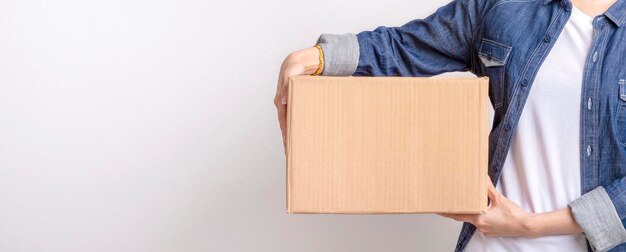 Photo asian delivering package with brown box isolated on grey background