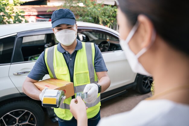 Asian delivery man accept credit card using a credit card reader while delivering products to customers at home, Cash on delivery concept with credit card.