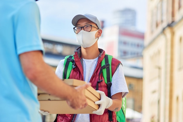 Asian delivery man giving pizza to customer