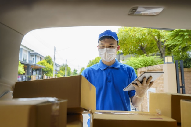Азиатский курьер службы доставки, работающий с картонными коробками на фургоне