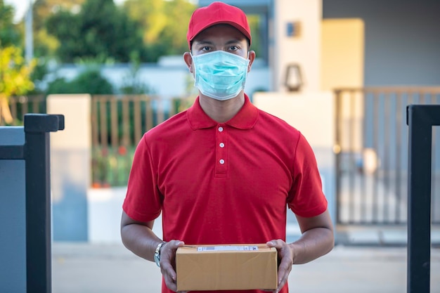 Asian Delivery man wear protective mask in red uniformOnline food and product delivery conceptNew normal in covid19